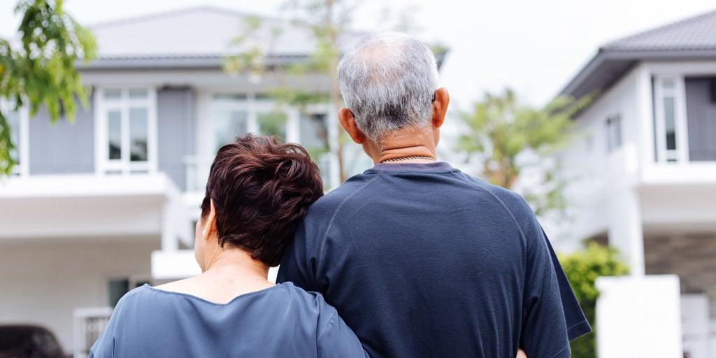 A back shot of a happy senior couple looking on from their house to the street.