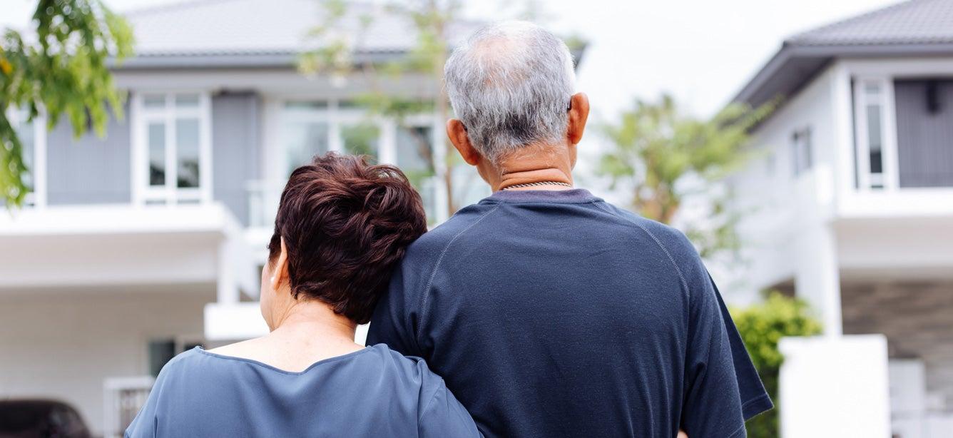 A back shot of a happy senior couple looking on from their house to the street.