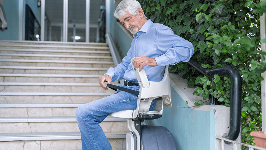 older man seated on outdoor stair lift