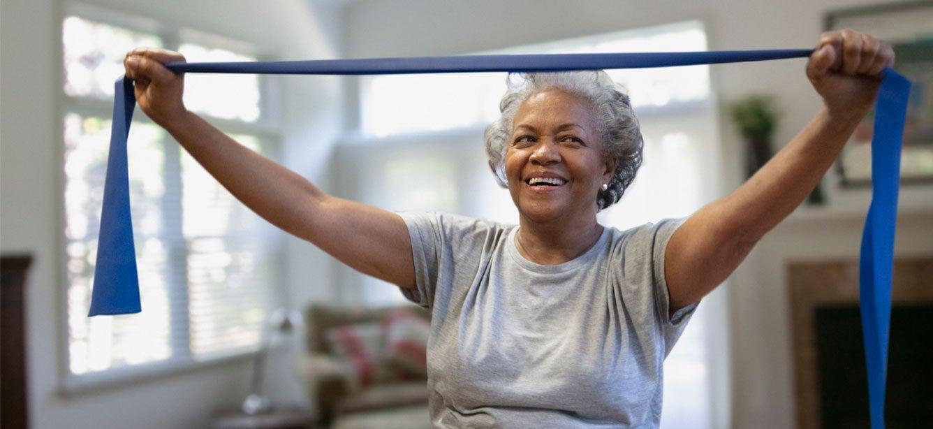 older black woman smiling while using resistance band overhead
