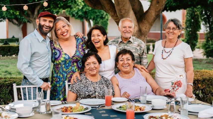 People posing for a group photo at dinner table.