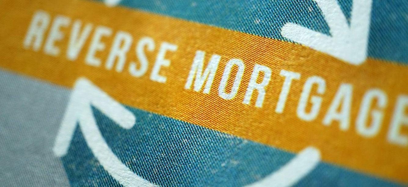 A close up visual concept of a recycle sign that has the words "reverse mortgage" inside of it.