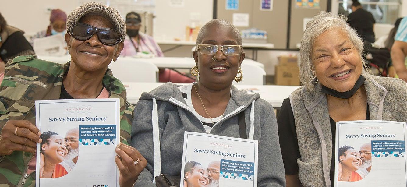 Three older Black women holding Savvy Saving Seniors guide