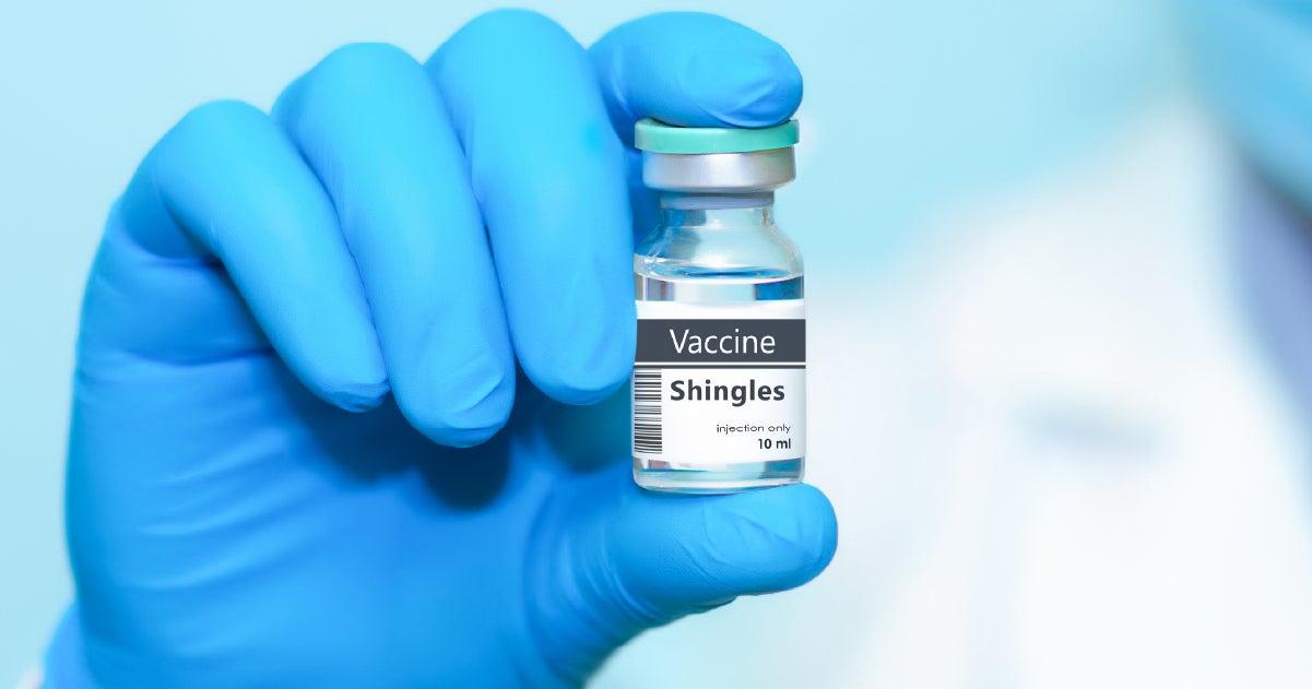 Close up of a Shingles vaccine vile held in a doctor's hand, who is wearing blue latex gloves.