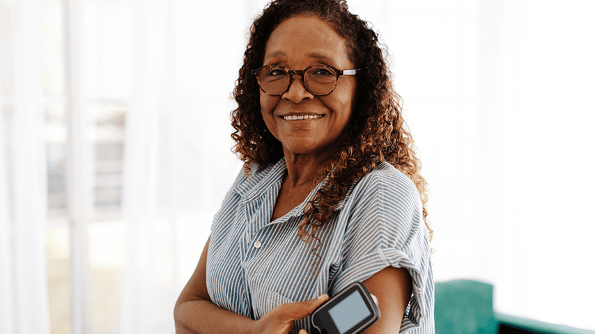 smiling older woman wearing glasses and checking glucose on arm