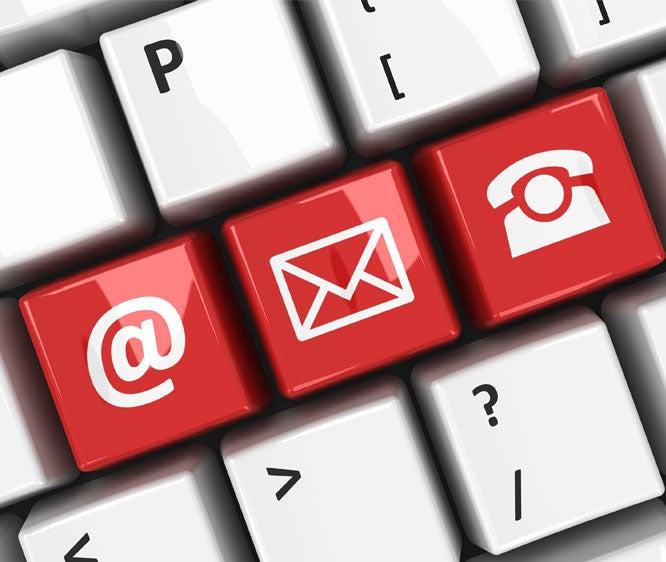 Close up picture of the "at" symbol, an envelope symbol, and a phone symbol on keyboard keys to signify getting in touch.